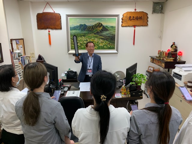 在總經理辦公室，總經理舉起像素風格的泡棉劍為完成闖關的新人「授勳」