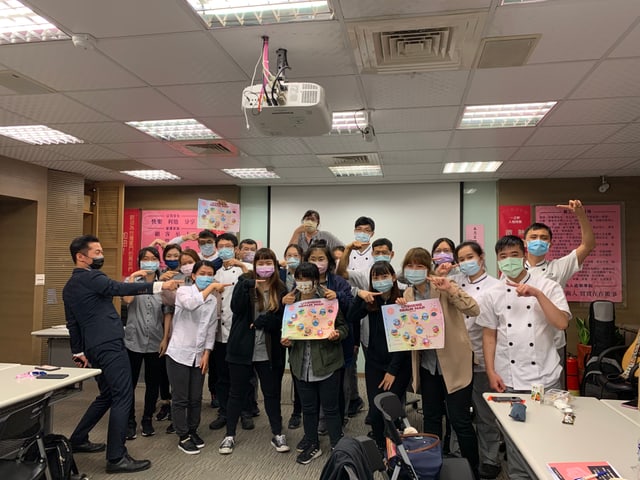 新人訓練場：新進同仁手持印好的闖關地圖海報合影，背景是公司文化、人格特質與員工自律信條的海報